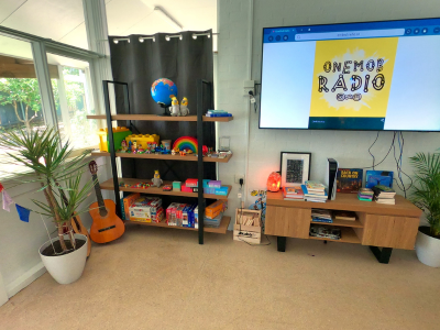 Entertainment area at the Coffs Harbour residential service. A large screen, bookcase, guitar, and various knick knacks can be seen.